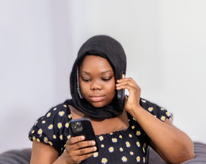 Goodness Abraham checking her phone, headphones on.